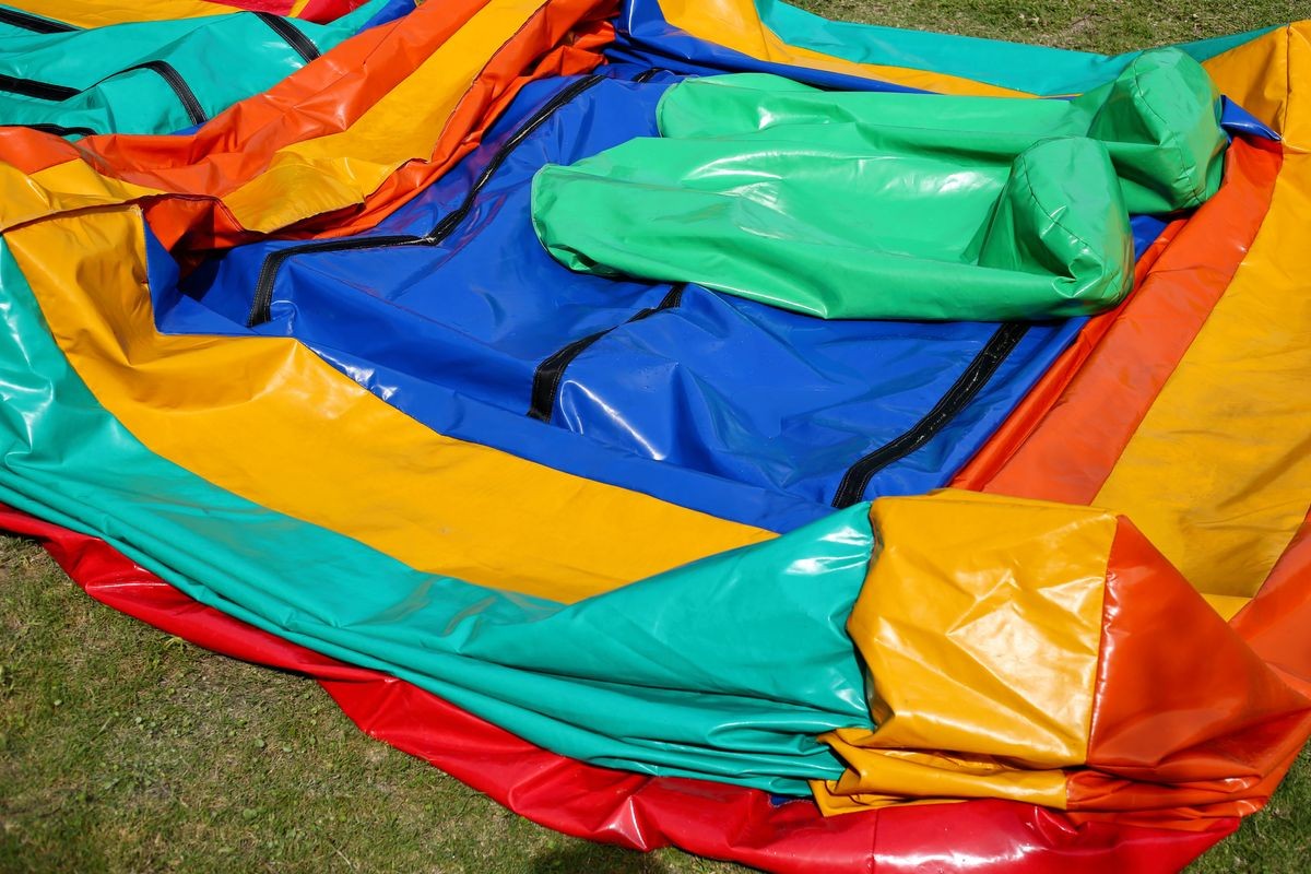 A colorful deflated jumping castle on a green lawn. This image can be used to represent the concept of a party being over or the setting up for an event. 